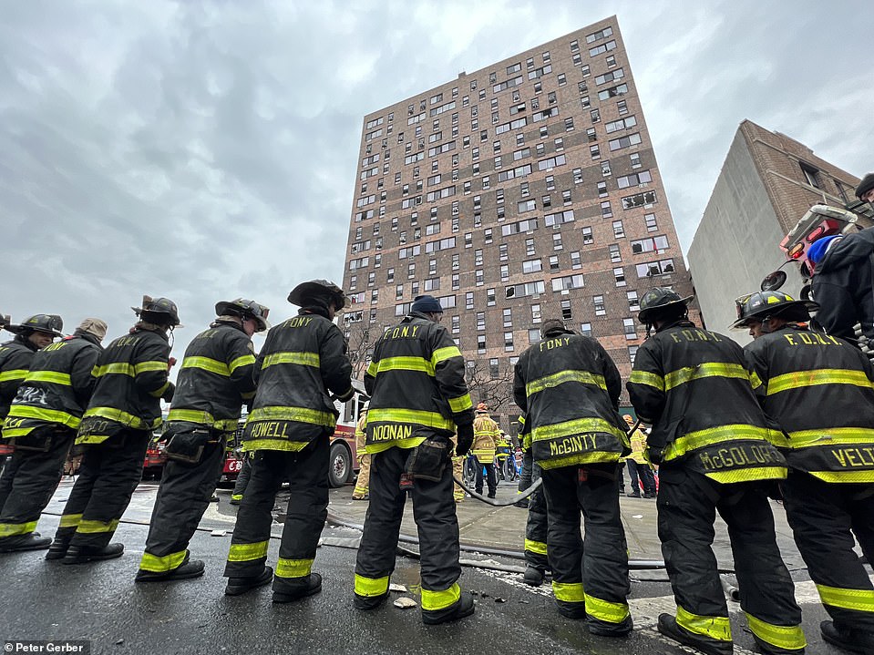 Firefighters stand in front of the apartment building at 333 East 181st Street in the Bronx
