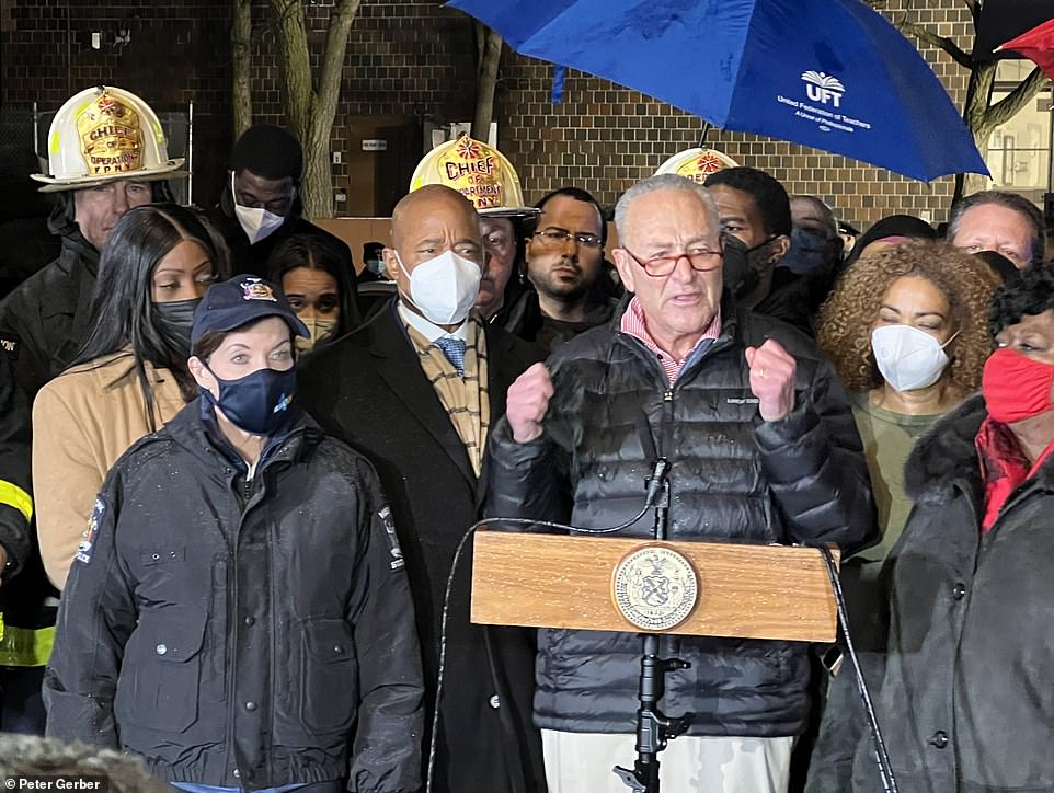 Chuck Schumer, senator for New York, speaks on Sunday evening at the scene of the fire, with the governor, Kathy Hochul, beside him and the mayor, Eric Adams, behind him