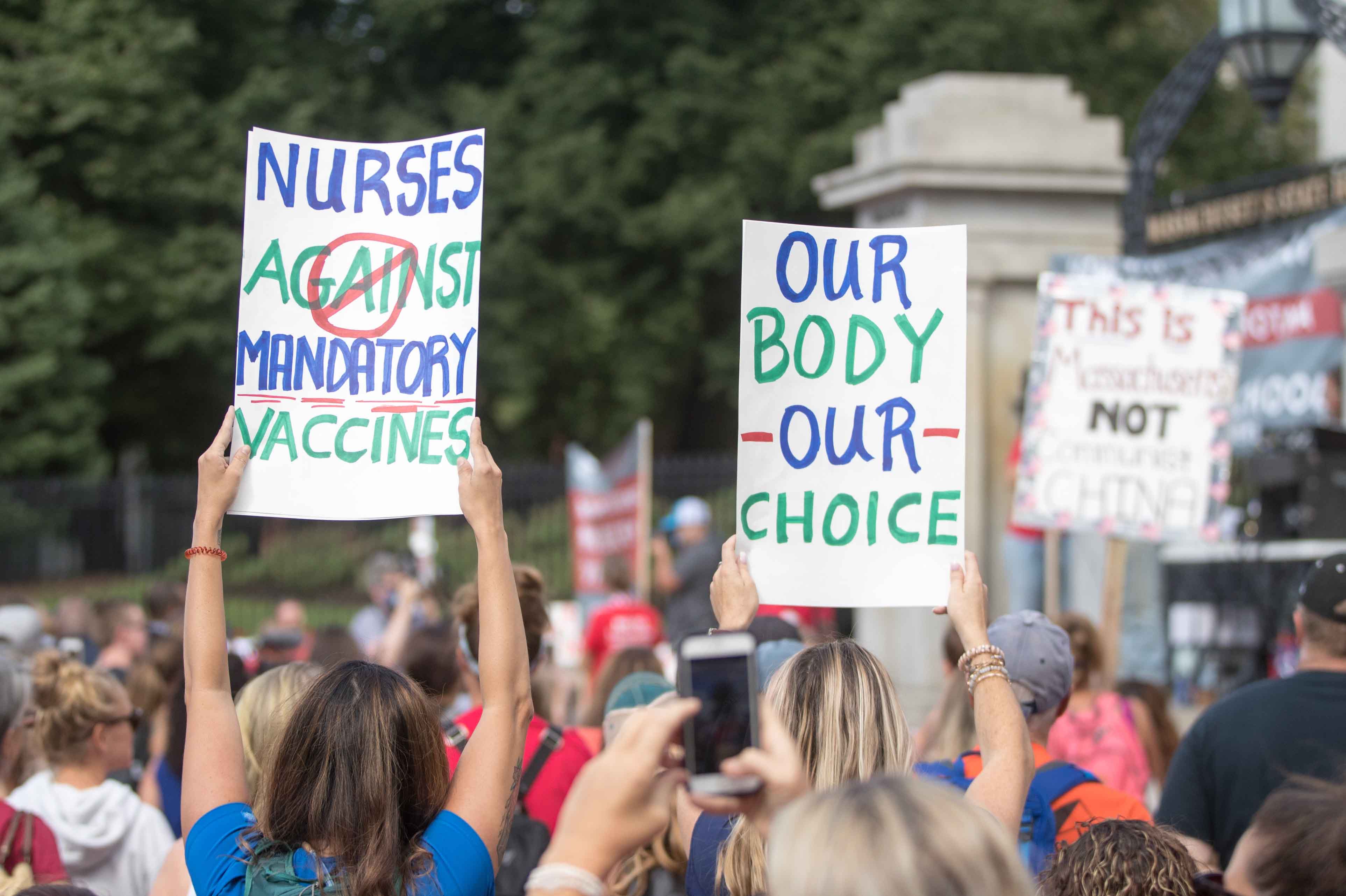 Anti-vaccine people hold up signs during a protest in front of the Massachusetts State House. 