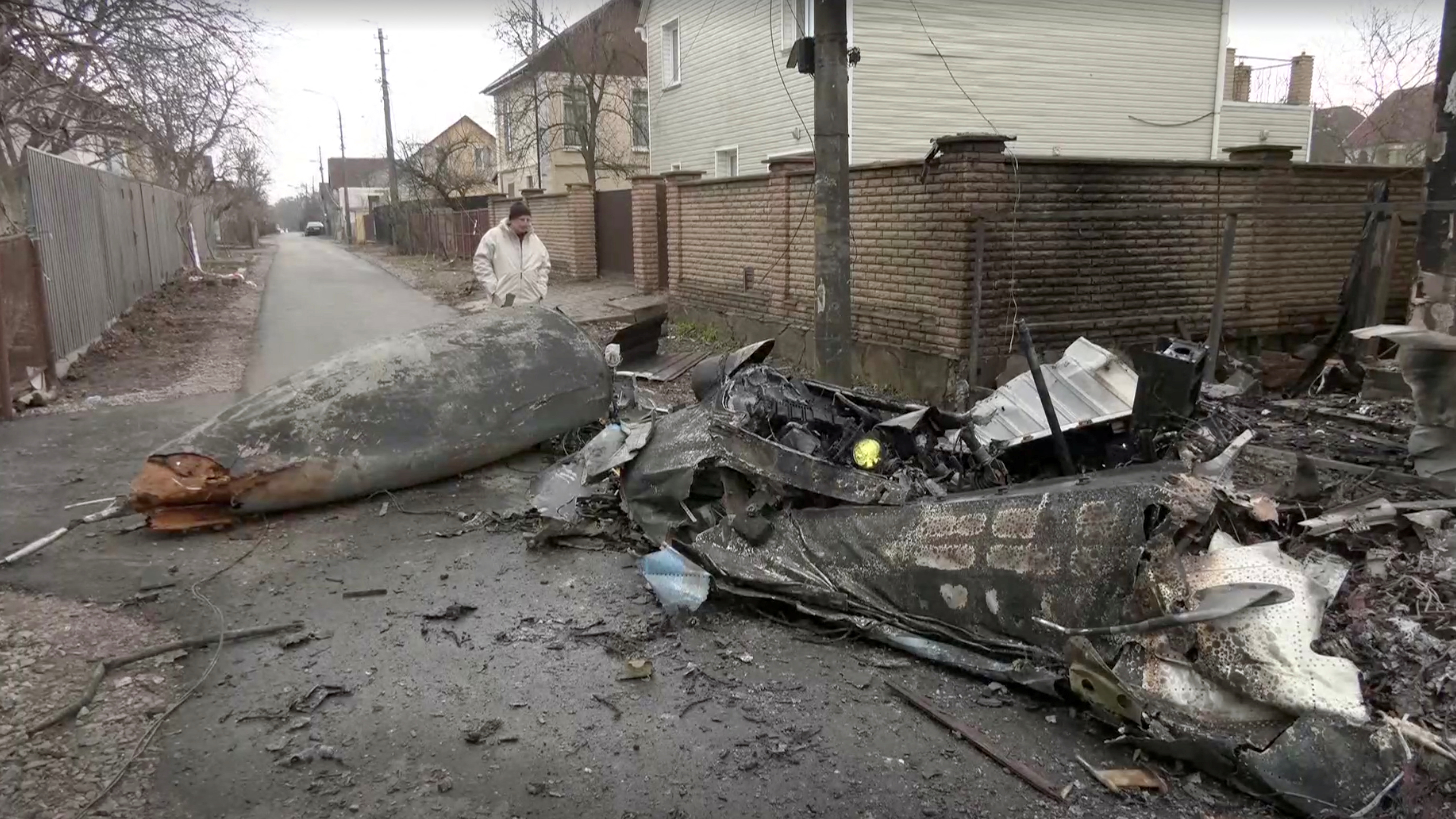 Screengrab from video shows a person inspecting the wreckage of an unidentified aircraft that crashed into a house in a residential area, after Russia launched a massive military operation against Ukraine, in Kyiv February 25, 2022. Reuters TV via REUTERS