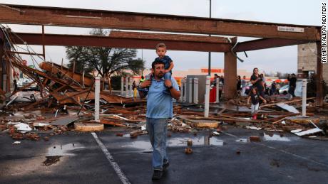 Arturo Ortega and his son Kaysen Ortega, 2, survey the damage Monday to a shopping center after a reported tornado touched down in Round Rock, Texas. 