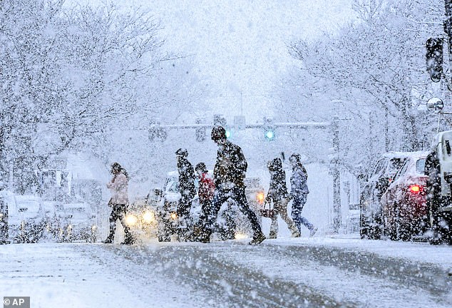 School districts from Kansas City to Pittsburgh have already announced closures. Above, people walk across Main Street as snow falls in Brattleboro, Vermont on Wednesday