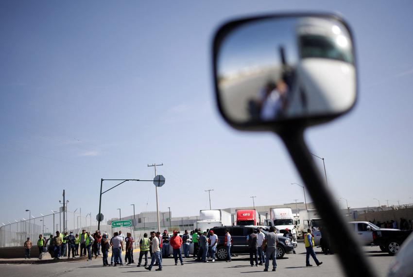 Truckers returning from the United States wait near their trailers, stranded at a protest against truck inspections imposed …